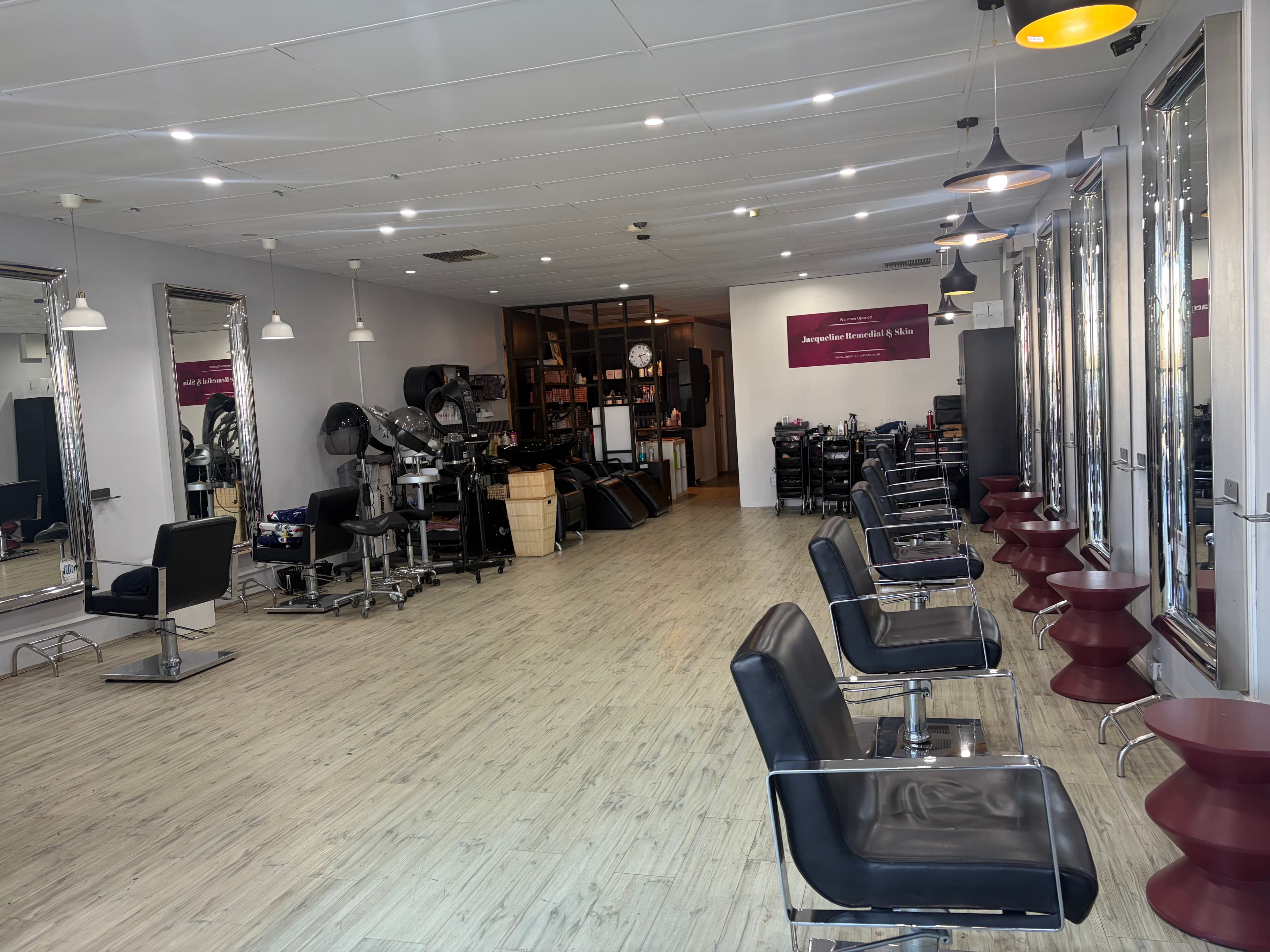 The salon floor: white walls, chrome mirrors and wine stools